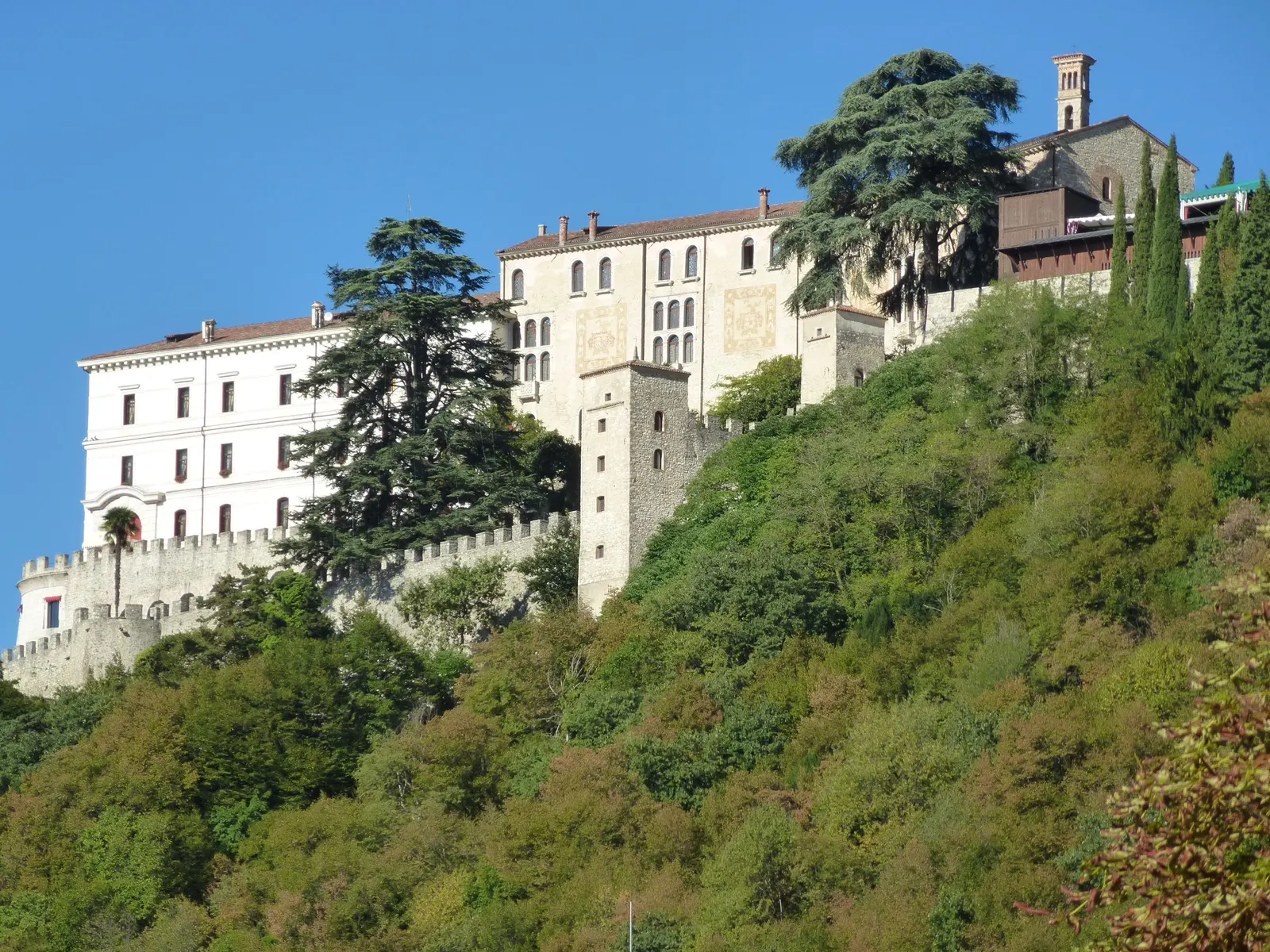 Mauern und Gebäude von CastelBrando auf dem bewaldeten Hügel über Cison di Valmarino
